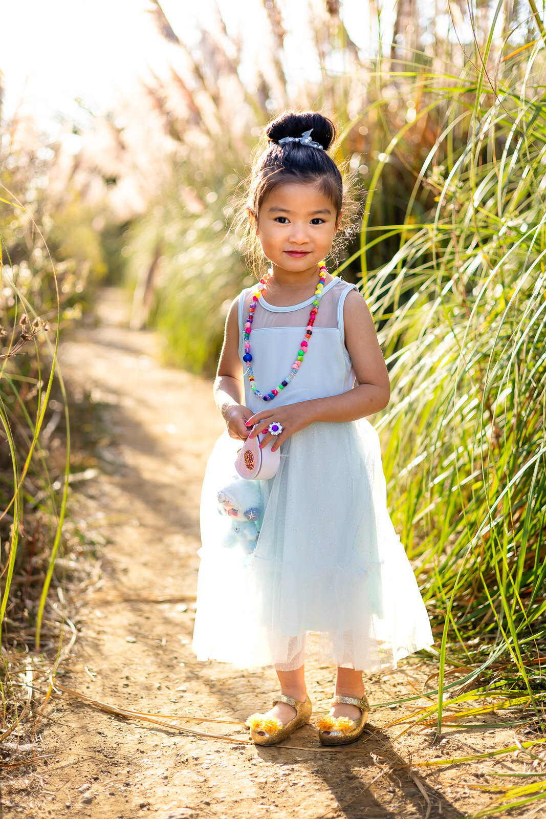 Little girl smiling in sunlight with toy and necklace – Bay Area Family Portfolio by Ellobelle Photography
