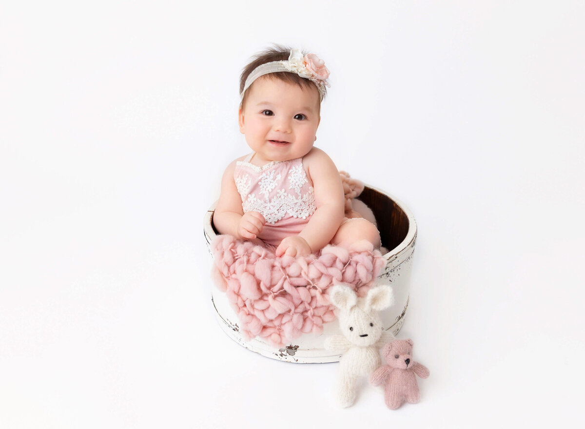 Classic and Timeless baby portraits done in Brooklyn. Baby girl in pink sitting and smiling 