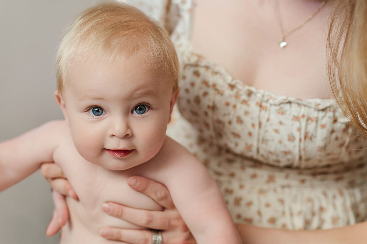 Baby boy sitting on his mothers lap, smiling by Lancaster PA photographer
