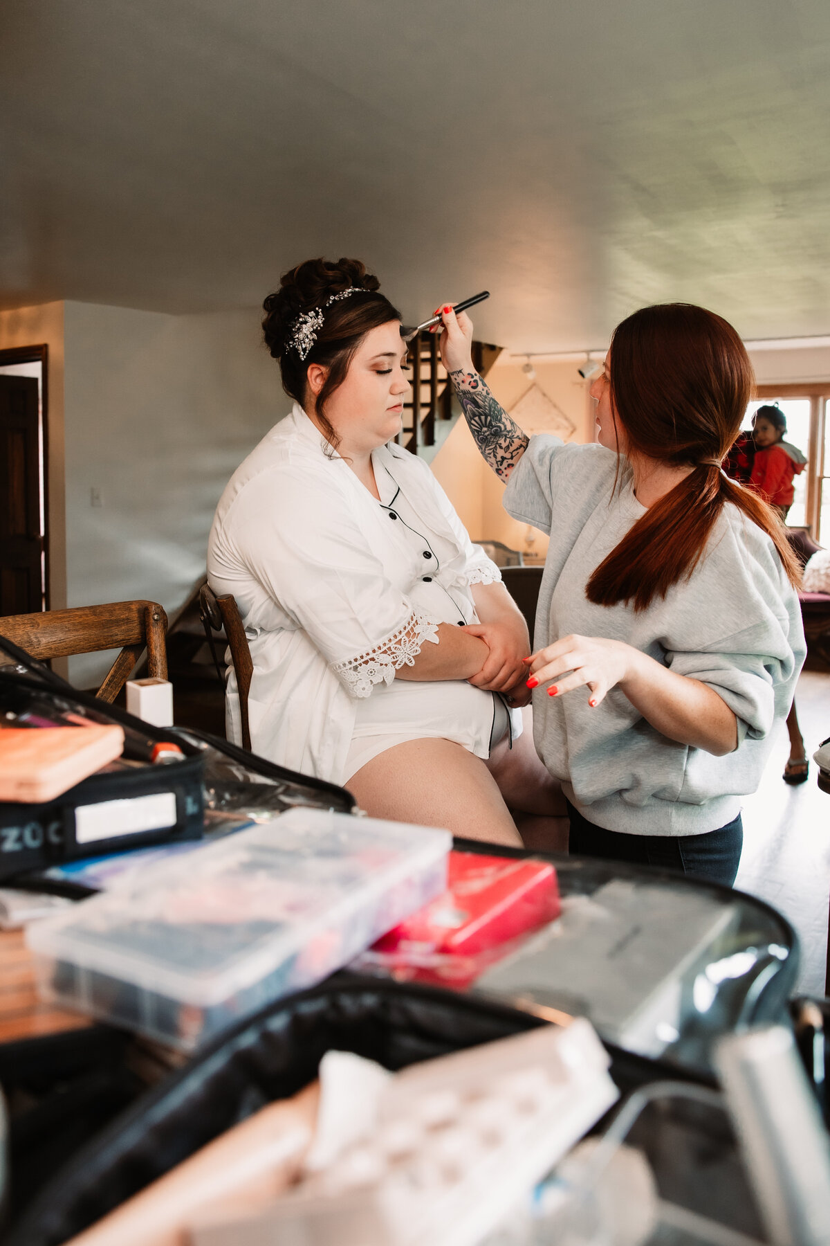 A bride sits while getting her makeup done