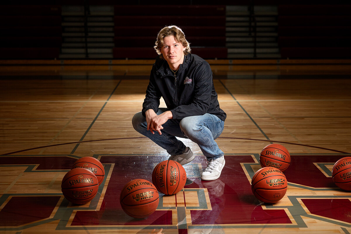 Senior guy posed in a gymnasium with basketballs