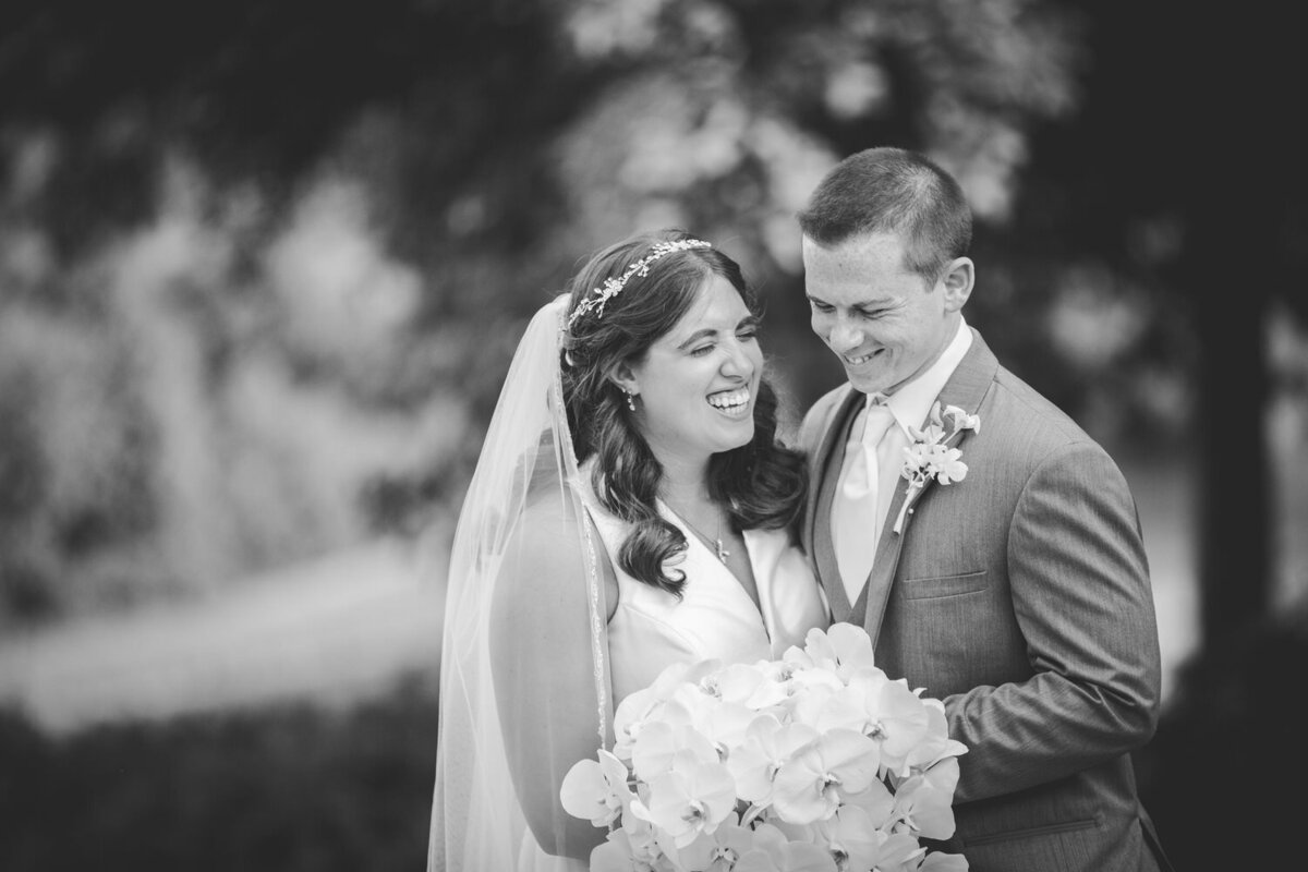 Bride and Groom laugh in a black and white portrait on their wedding day