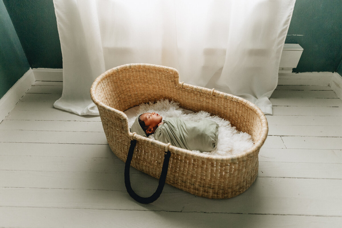 Infant photographer capturing newborn baby sleeping in a crib.