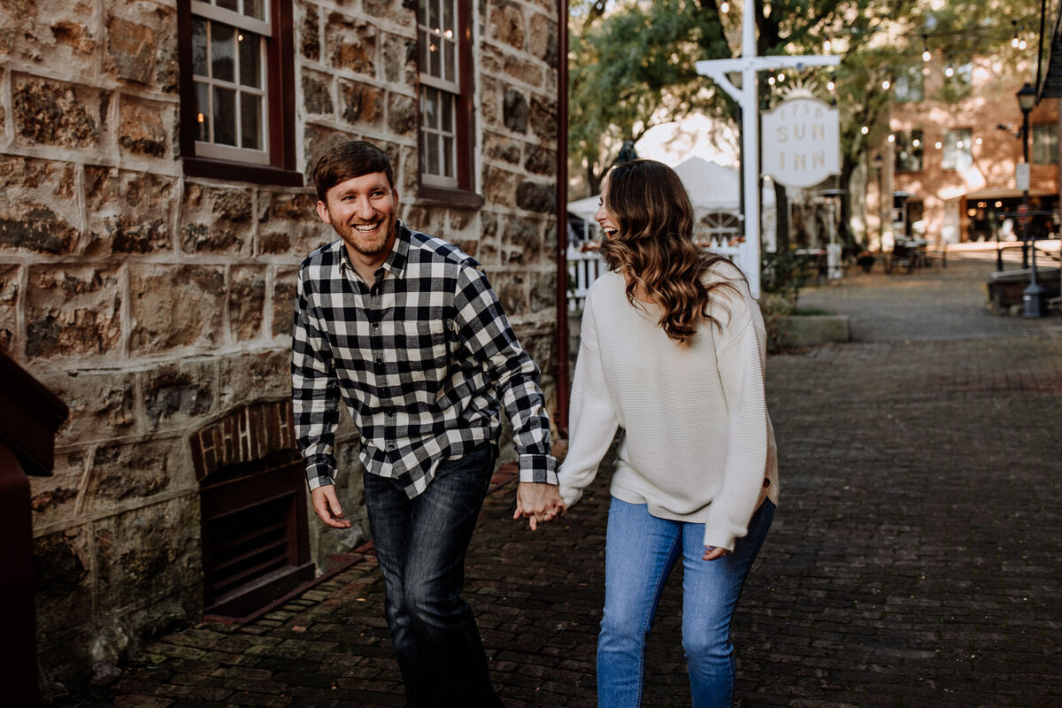 Bride and groom holding hands looking at each other while standing in front of rolling hills with the sunlight coming down on them