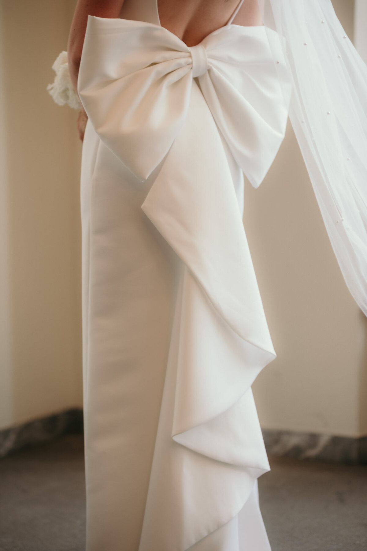 Eine Nahaufnahme der großen Schleife am Rücken des Kleides der Braut.