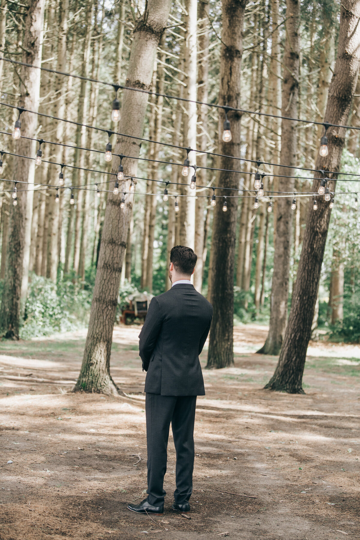 A groom waiting for his bride in an enchanted forest for a romantic first look