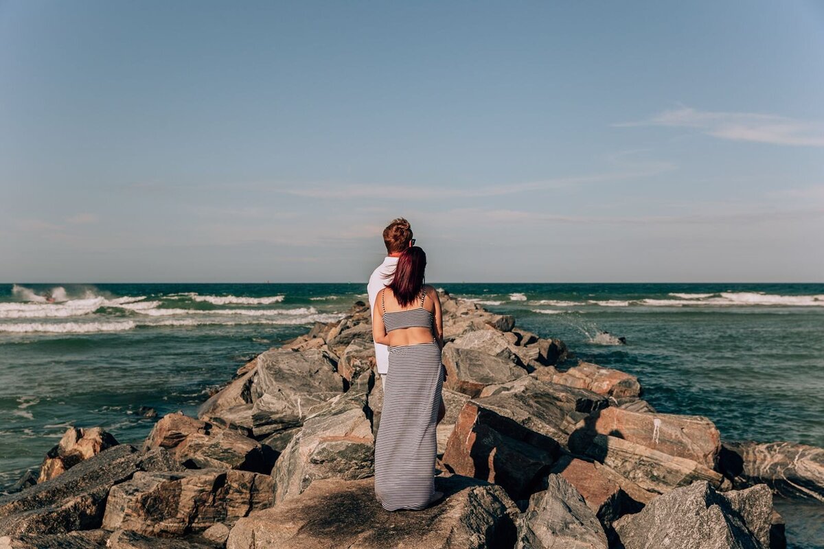 couple standing on jetty rocks in new smyrna looking out into the ocean