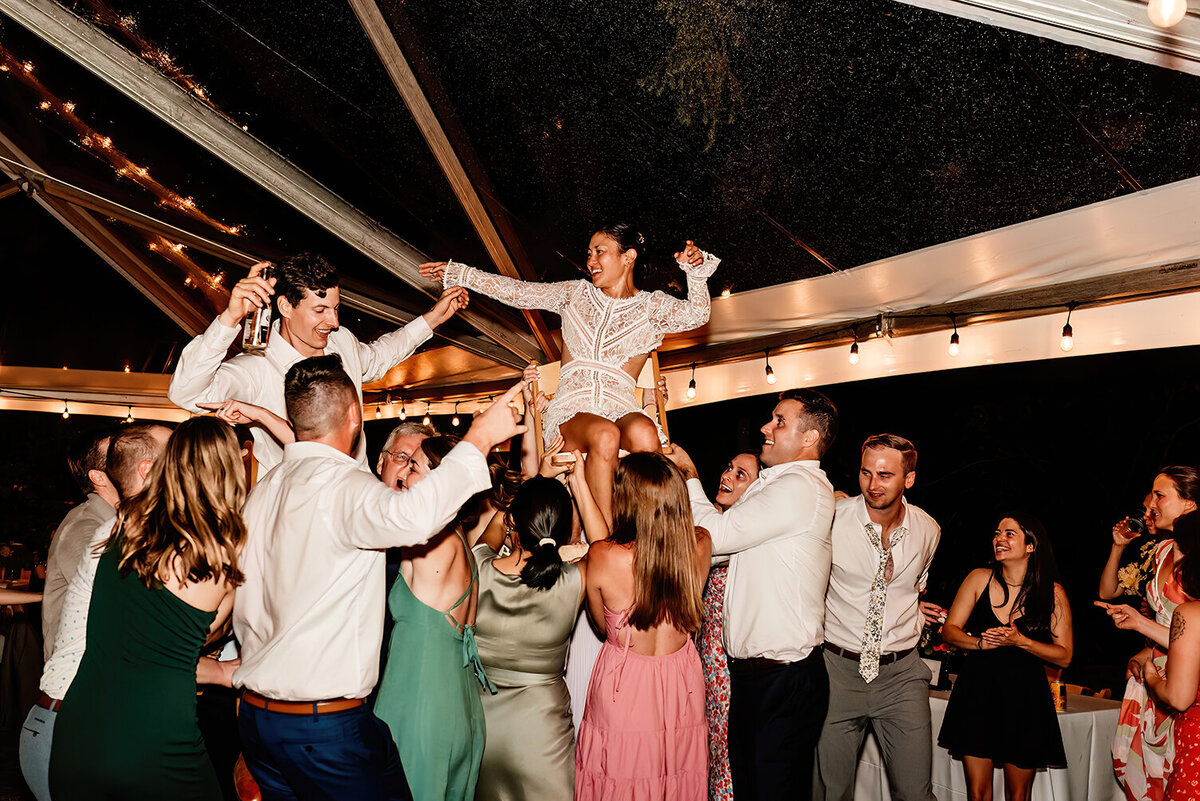 a husband and wife being hoisted up on chairs during their reception