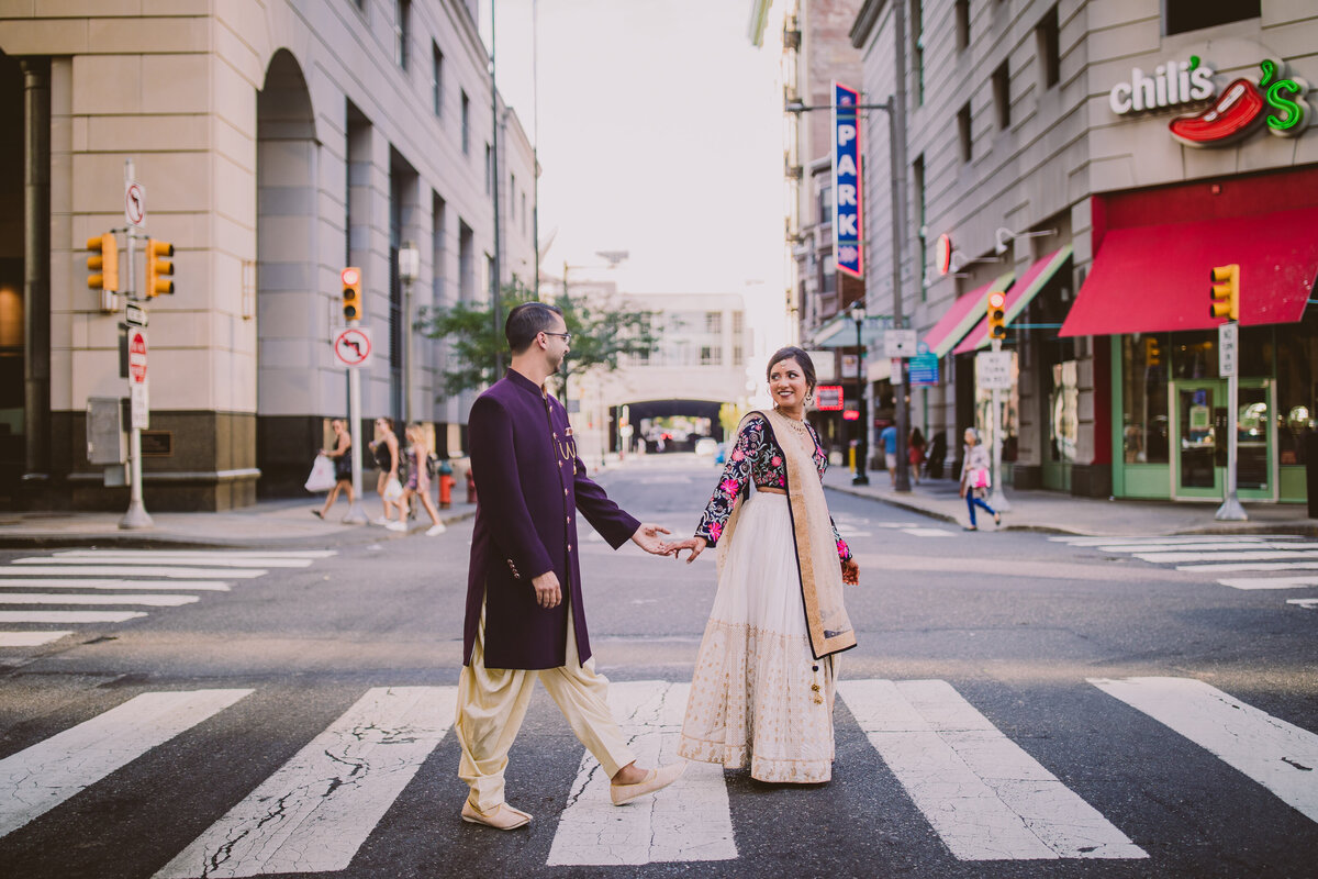 Indian bride and groom on their sangeet day walking across the street outside the marriott downtown philadelphia