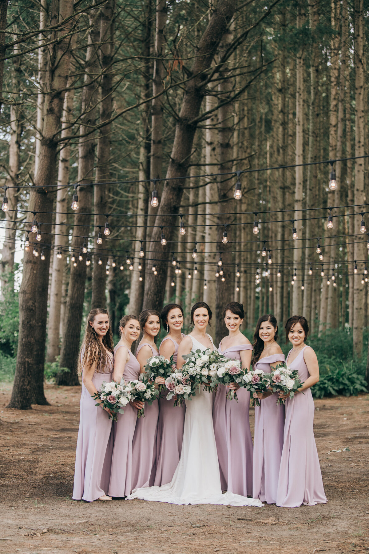 Elegant bridesmaids wearing lavender dresses while posing for photos in an enchanted forest