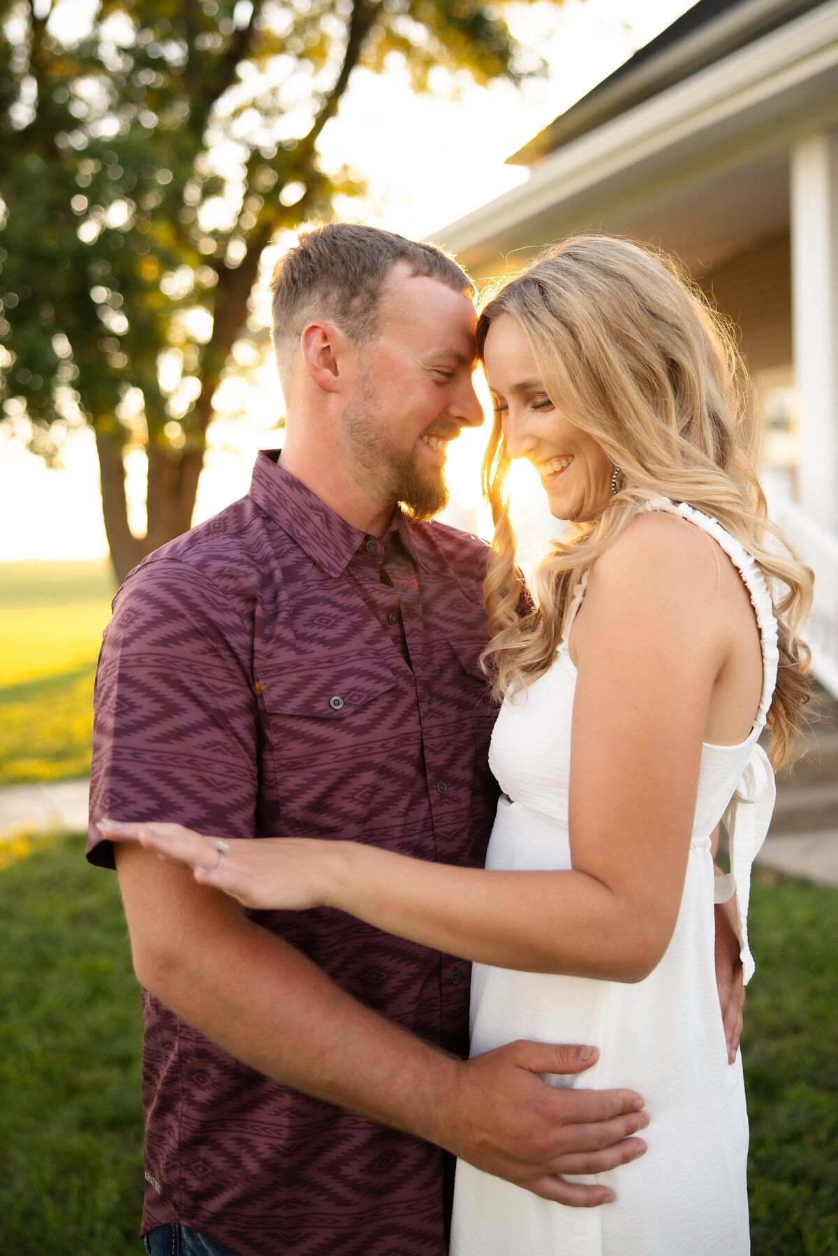 Couple embracing with man looking at woman who is looking at ring with beautiful light
