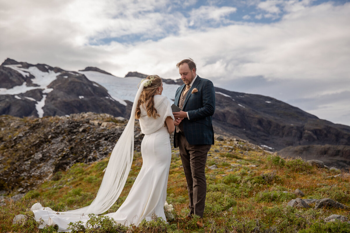 A groom reads his vows to his bride during their adventure elopement ceremony in Alaska.