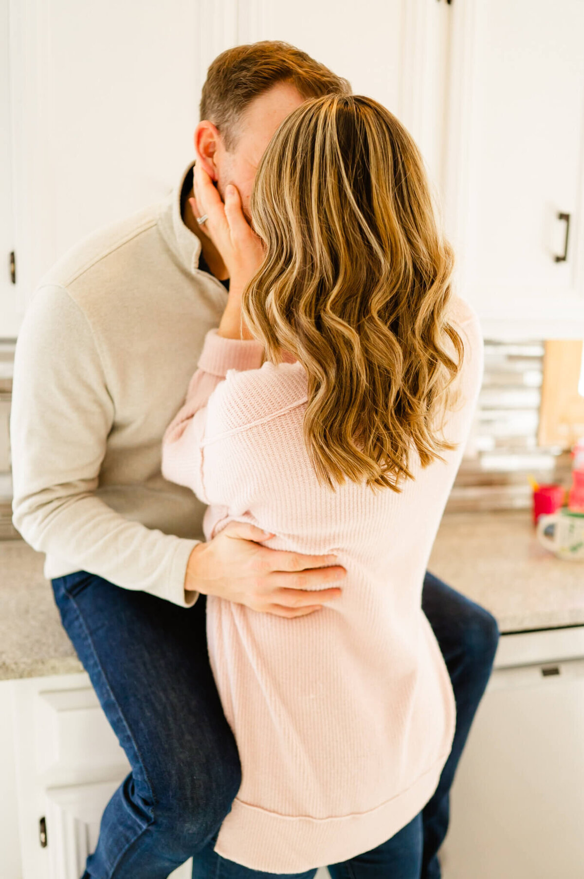 Woman kissing man in kitchen during a couples session near Naperville, IL.