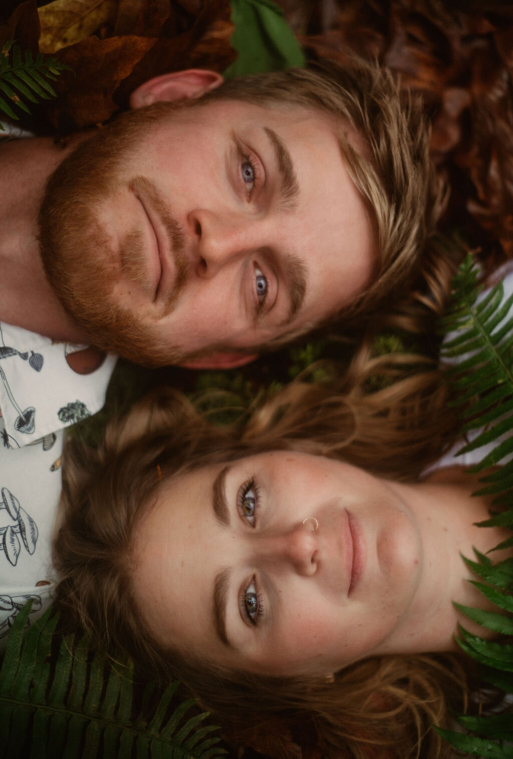 couple portrait laying on forest floor with ferns