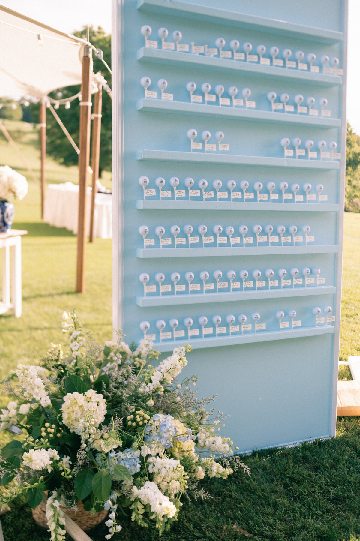 Blue seating chart assignment stand with sailcloth tent in background