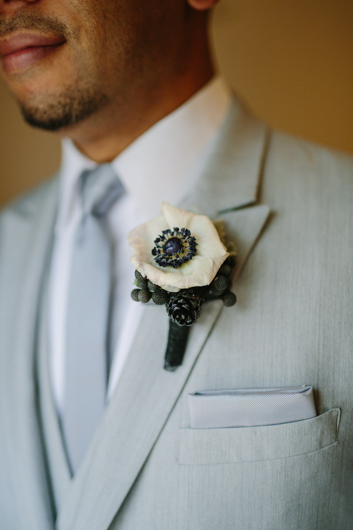 Groom floral detail boutonniere white anemone on suit lapel before wedding ceremony at The Gardens at West Green San Antonio