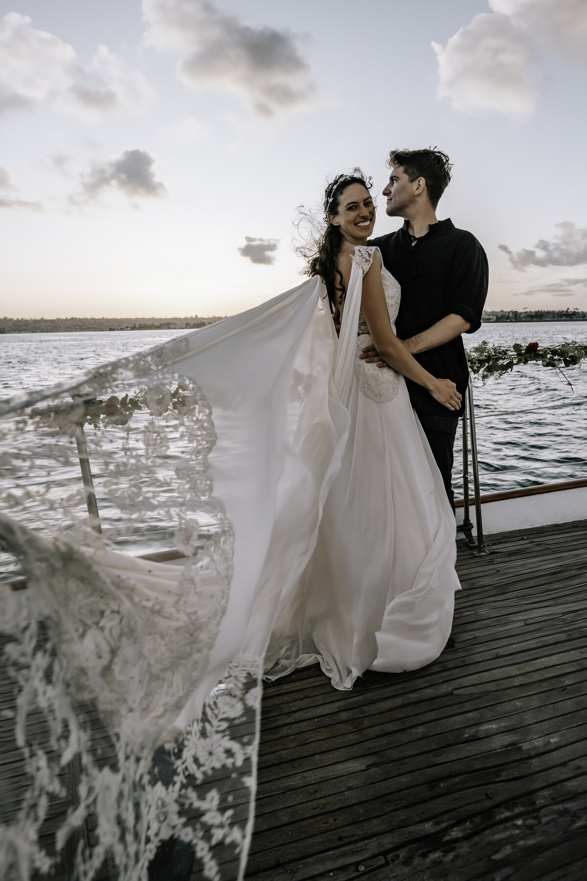 Bride and groom elopement on yacht in San Diego with the Claire Pettibone chiffon gown blowing in the ocean breeze
