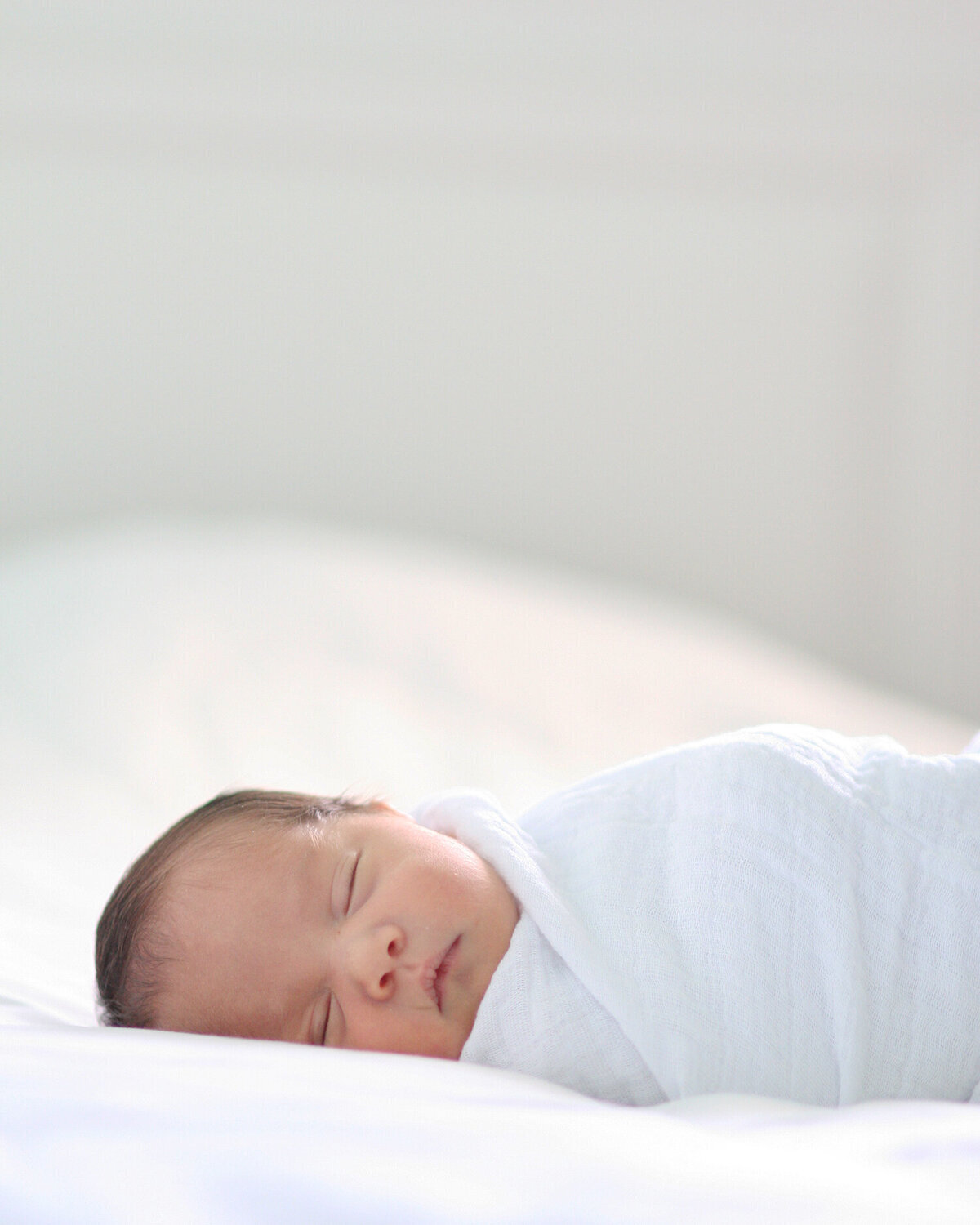 Peaceful baby sleeping on white bed — natural in-home newborn photography in San Francisco Bay Area