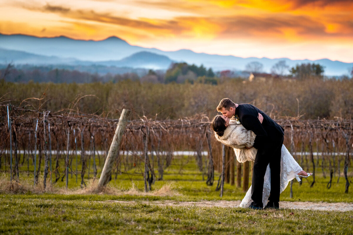 Dramatic sunset portrait of a couple kissing during sunset at Marked Tree Vineyard in Ashville, NC. Captured by Pittsburgh Wedding Photographer Michael Fricke Photography.