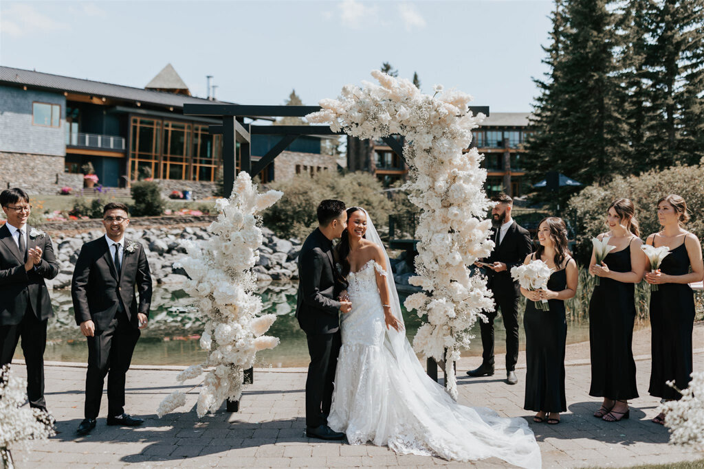 Couple in front of floral archway created by Foxglove Studio, contemporary Calgary, Alberta wedding florist, featured on the Brontë Bride Vendor Guide.