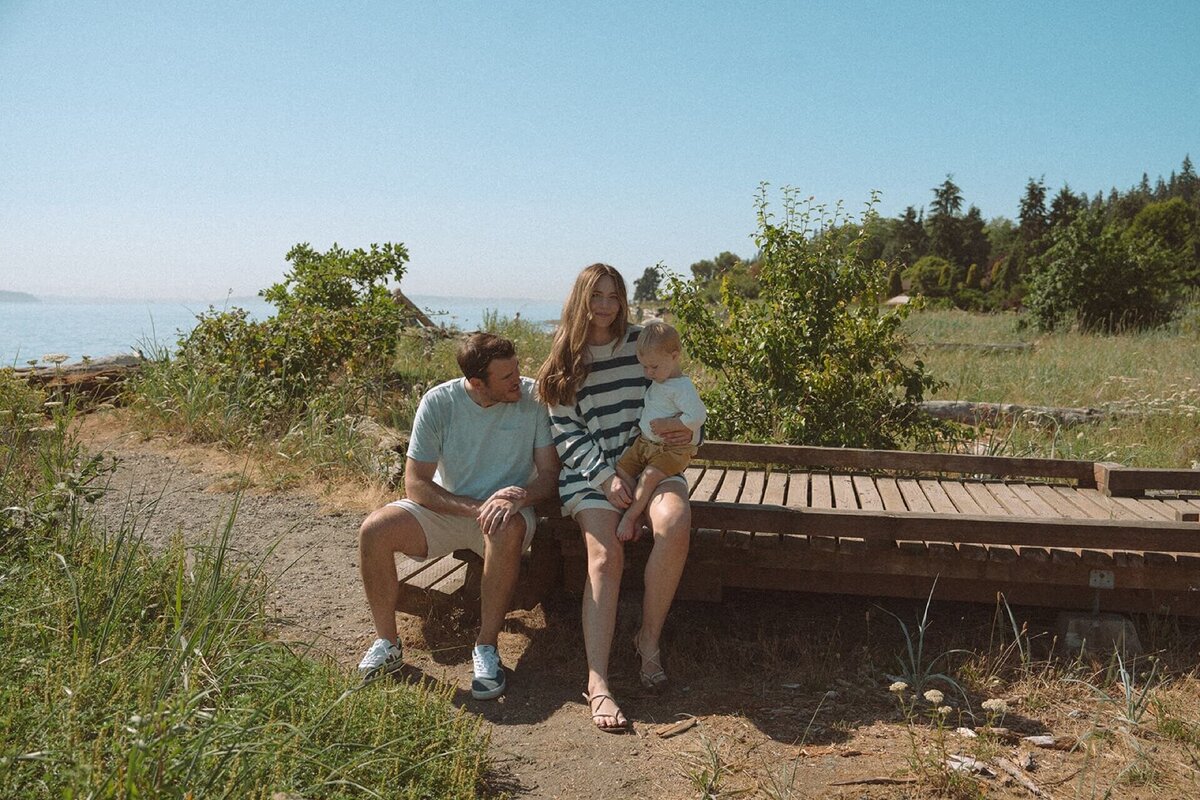 male and female sitting on beach boardwalk with baby son