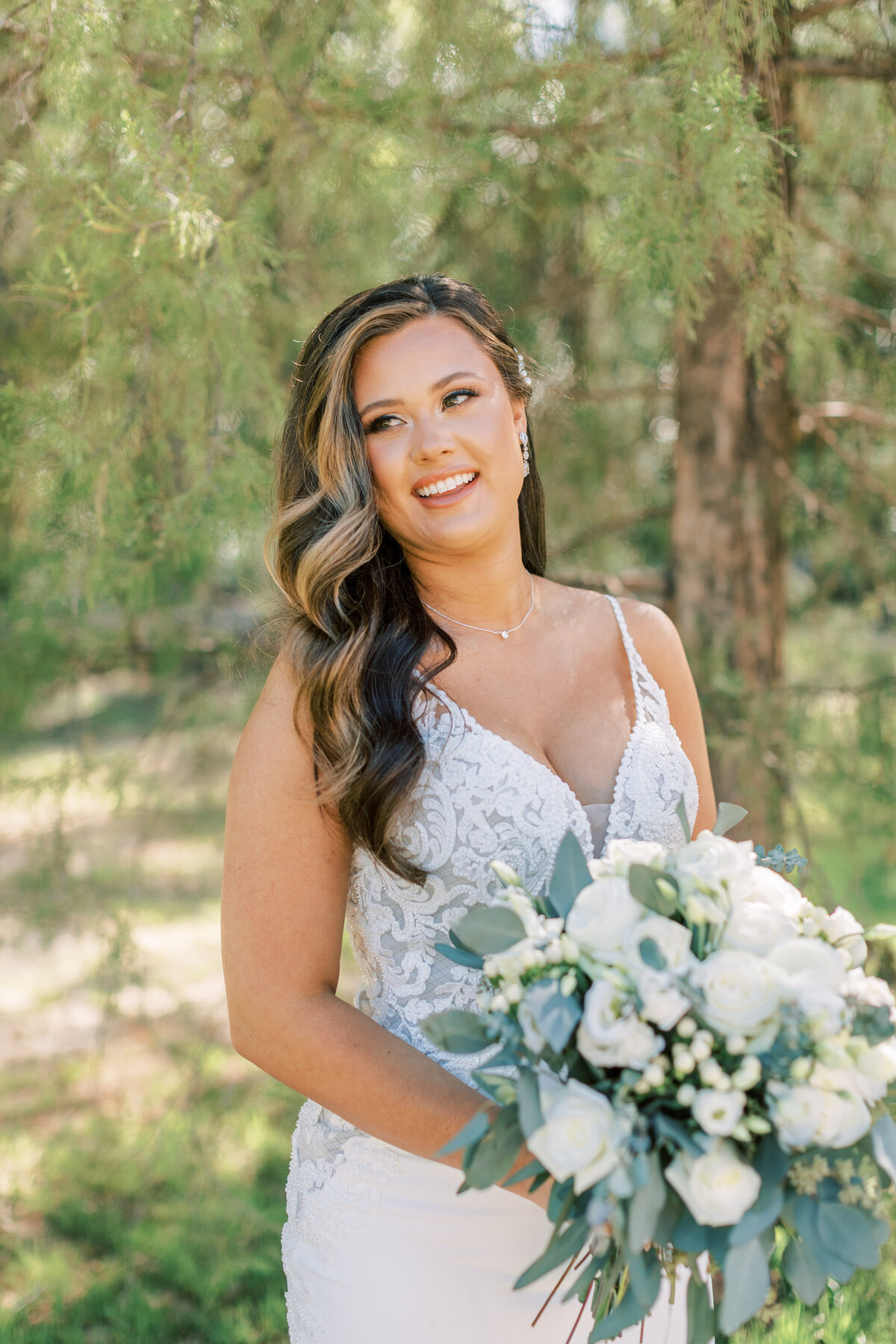 A stunning bride holds her bouquet and laughs off into the distance.