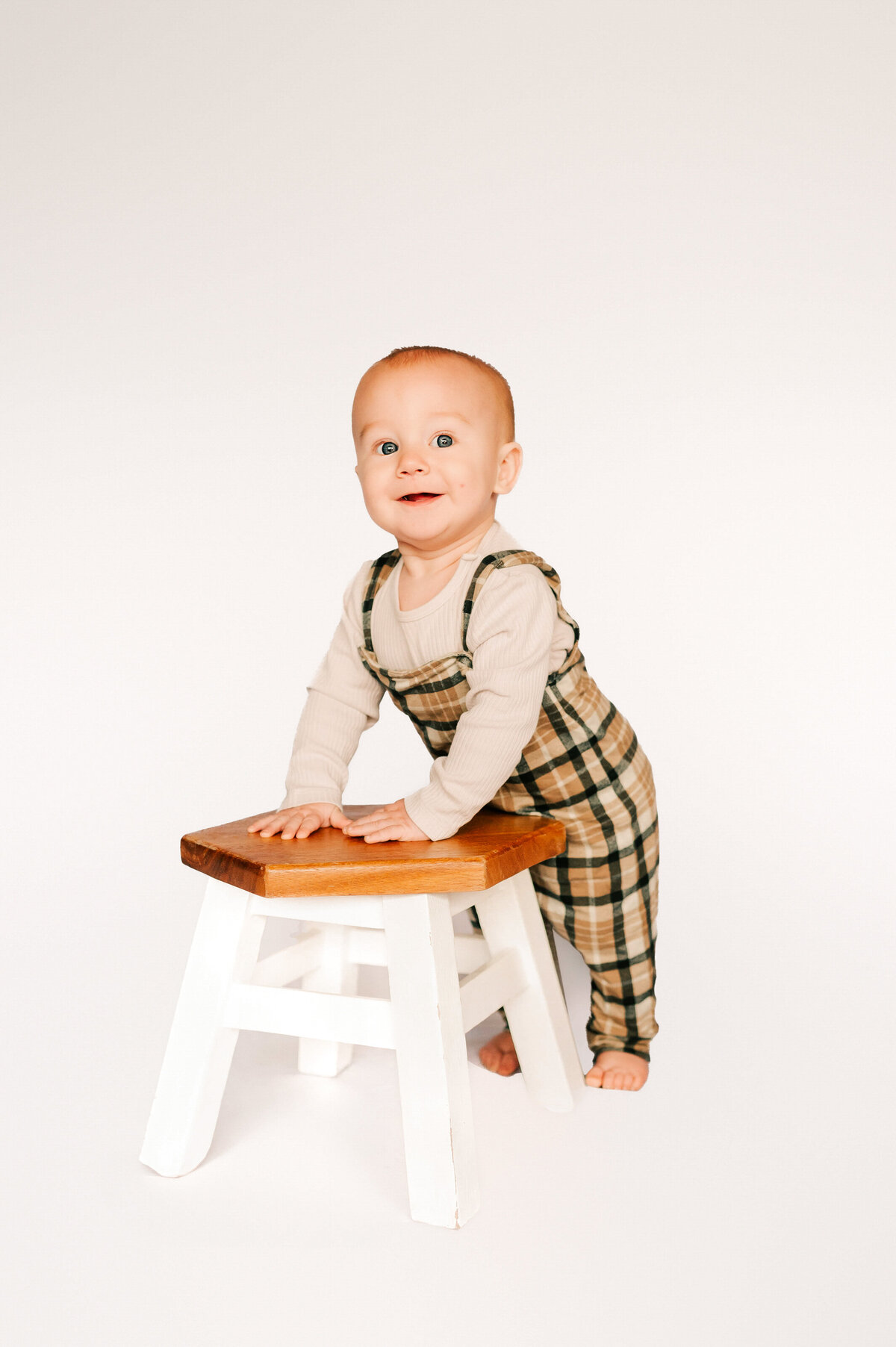 Springfield MO kids photographer Jessica Kennedy of The XO Photography captures toddler boy standing up near stool during 1st birthday milestone photography session