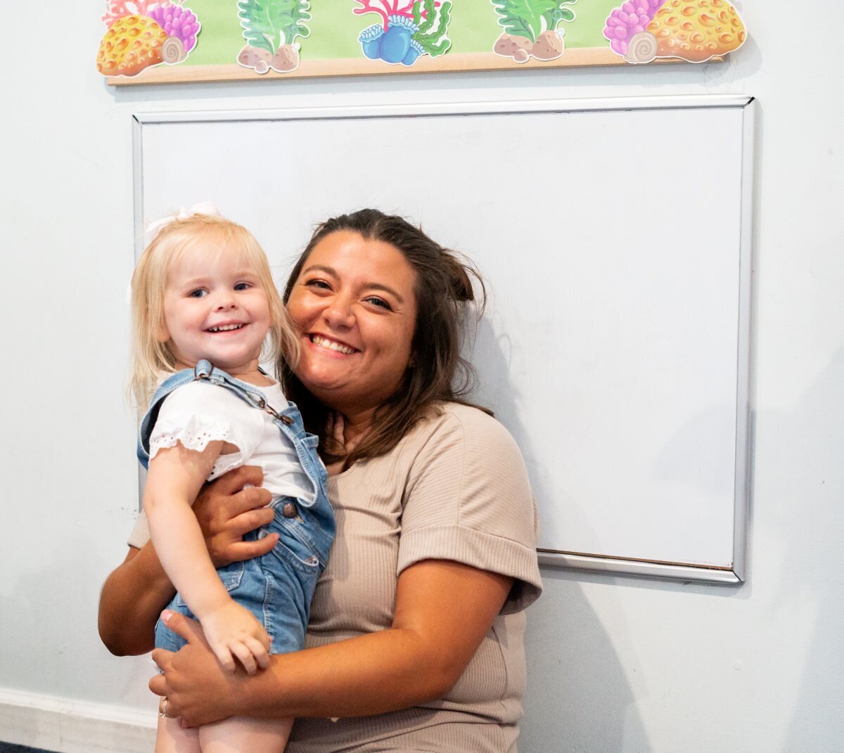 Ms. Mia smiling and laughing with a student in the classroom at The Nest, a preschool and learning center in Surf City, North Carolina