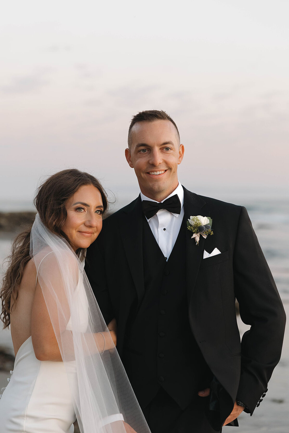 Bride and groom smiling on the beach at sunset