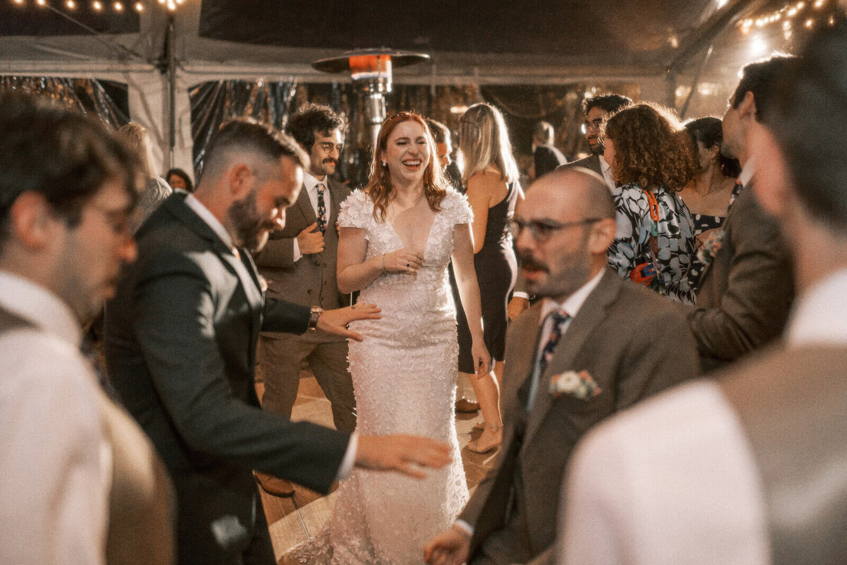 A bride smiling with people dancing around her during her wedding reception at Suttle Lake Lodge.
