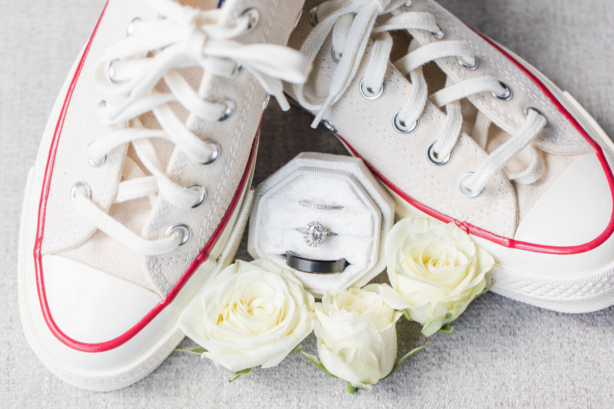 Wedding ring with wedding shoes and white flowers below it