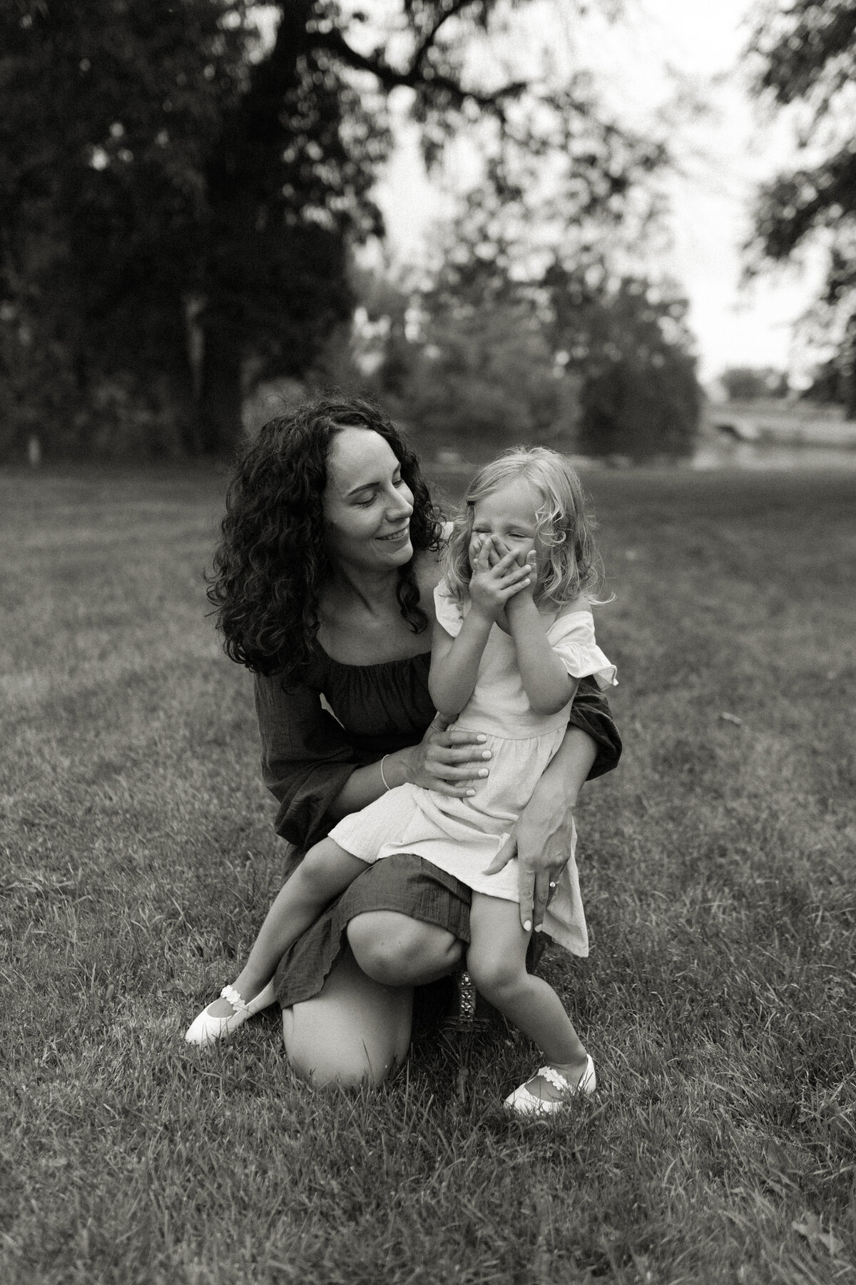 A little girl giggles on her mom's lap during summer family photos in Wisconsin.