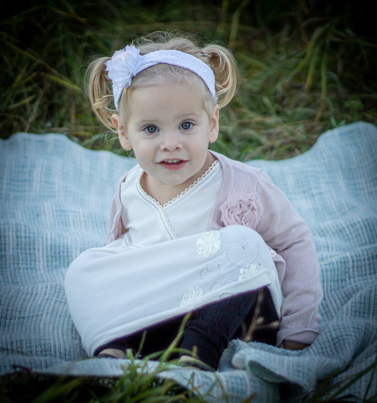 little girl with pigtails sits on a picnic blanket in Edmonton