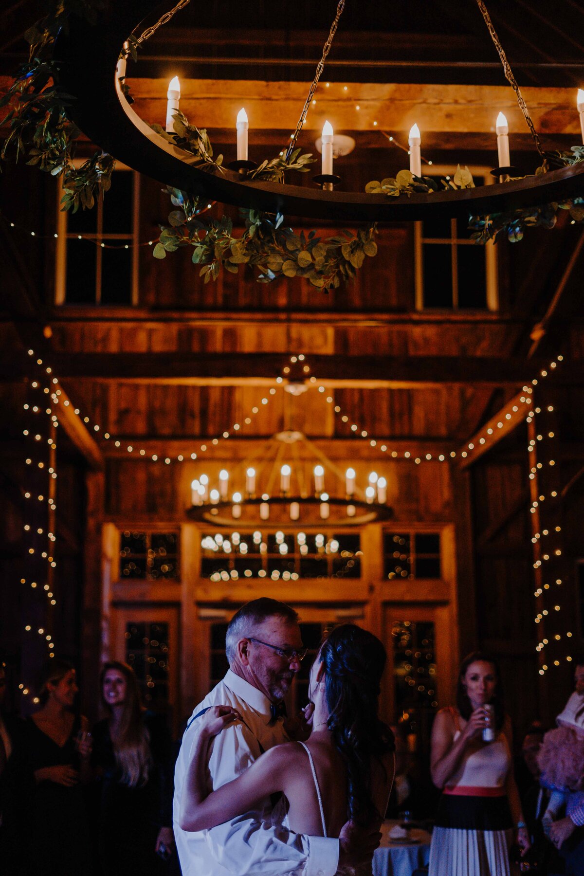 a dad and daughter dancing at wedding under candlelit chandelier