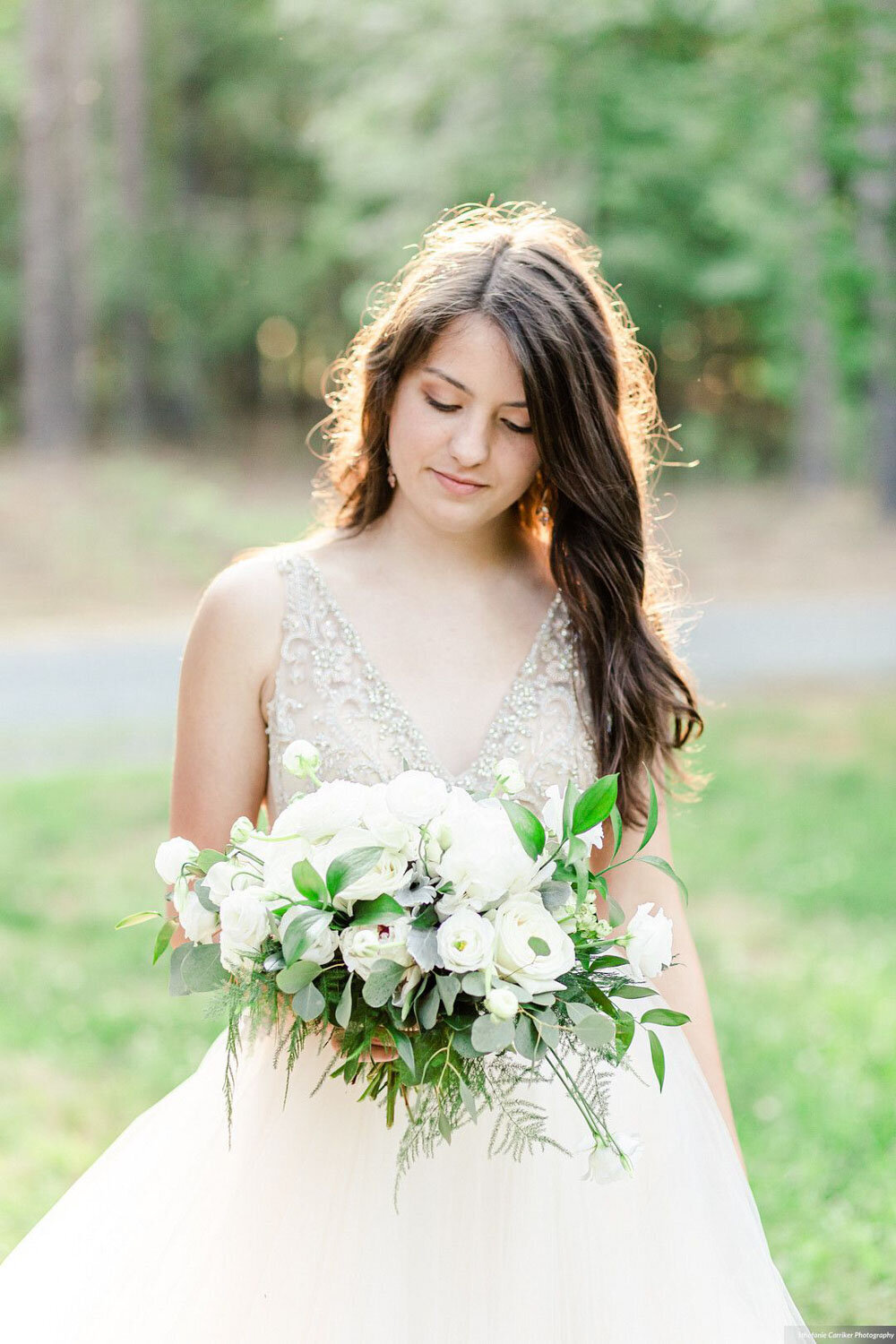 Bride holding a white floral bouquet, looking down thoughtfully