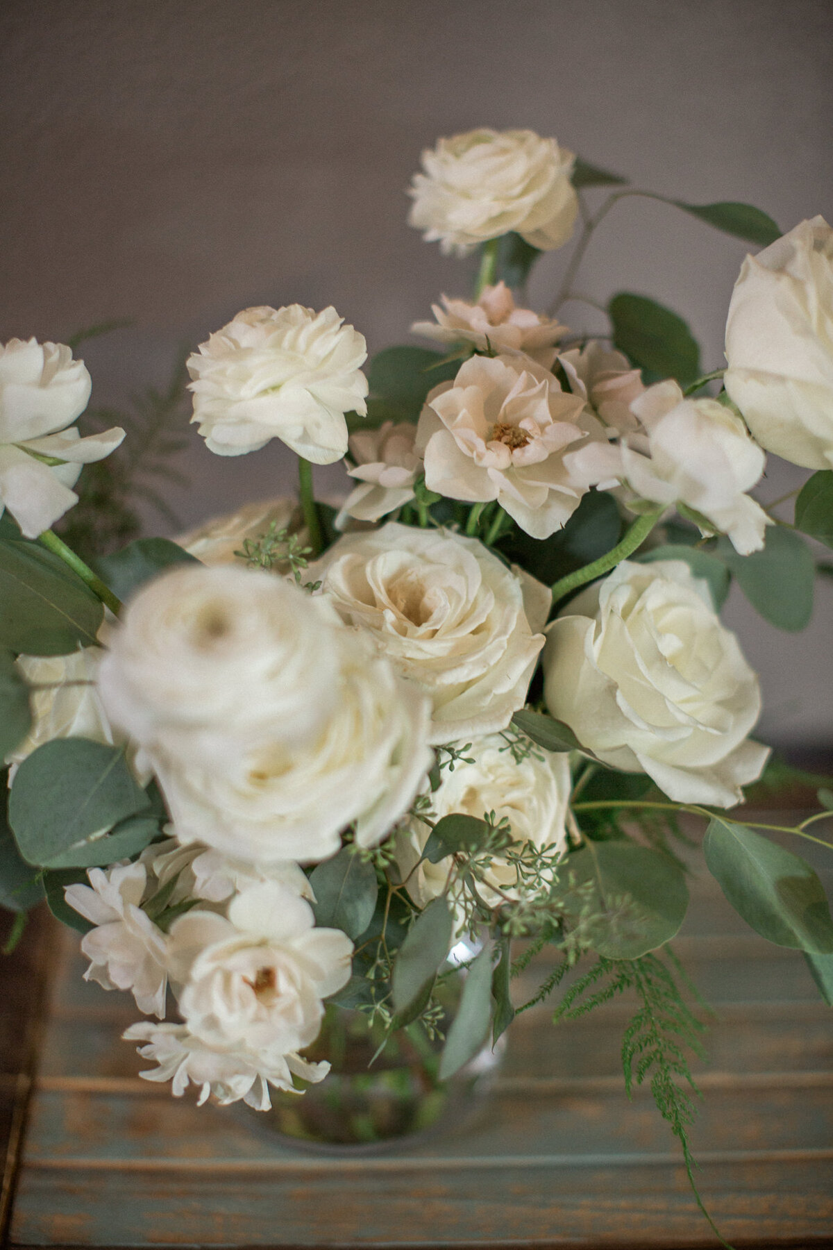 Close up image of a bridal bouquet of white roses, ranunculus and eucalyptus