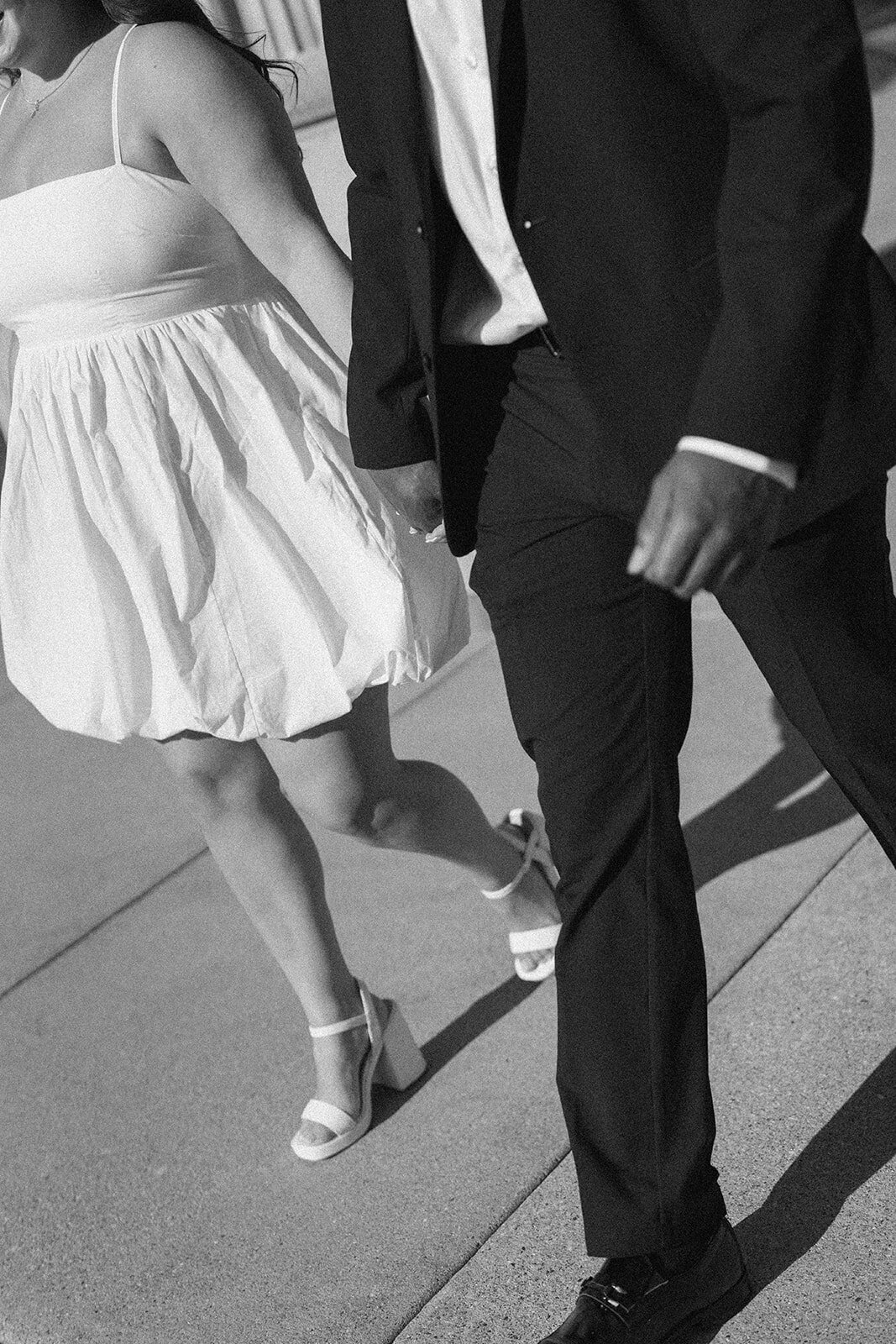 Romantic Kalamazoo engagement portrait with couple walking near arched stone windows.
