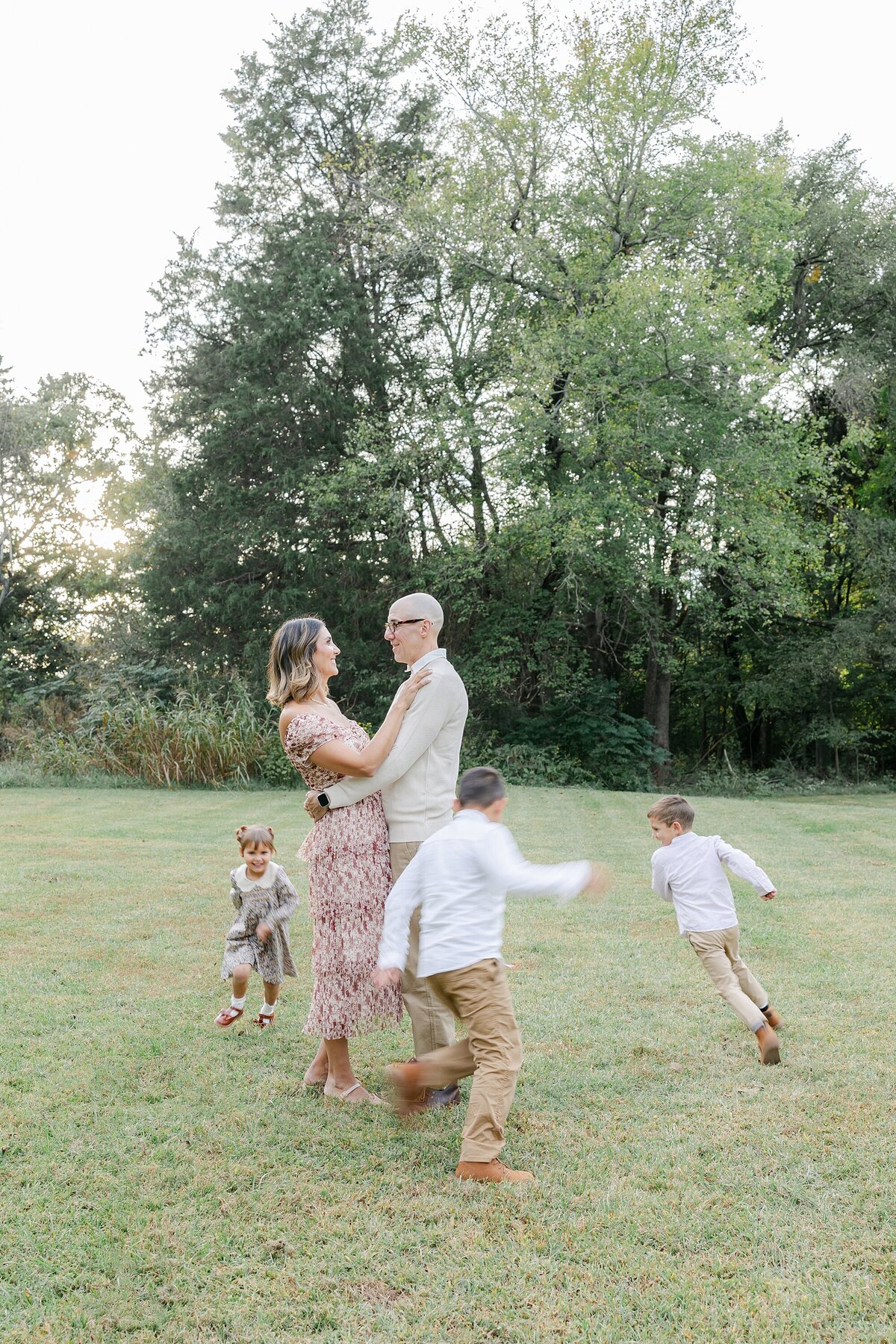 mom and dad looking at each other while children run around them
