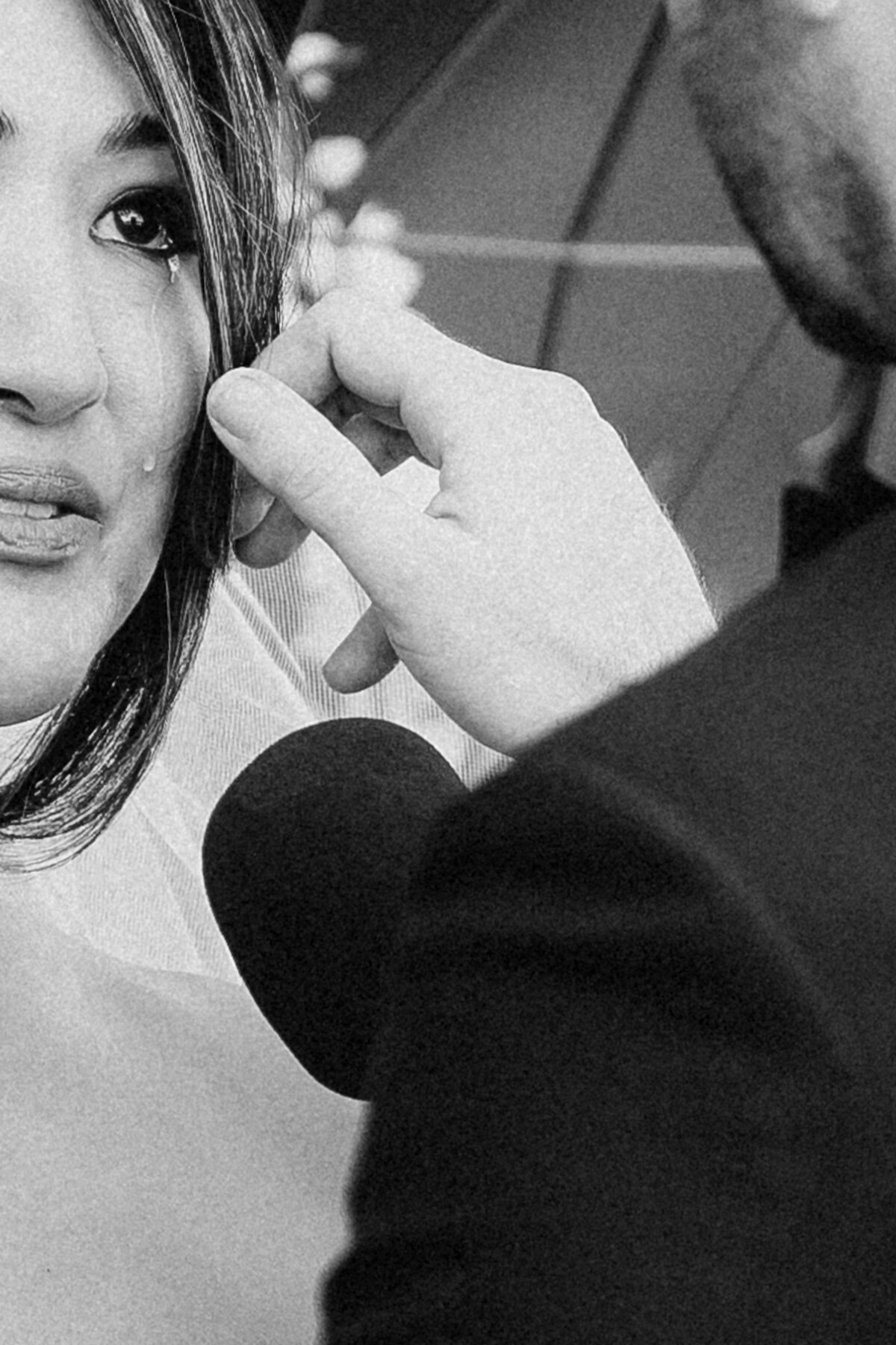 Close up of groom wiping away bride's tear in black and white
