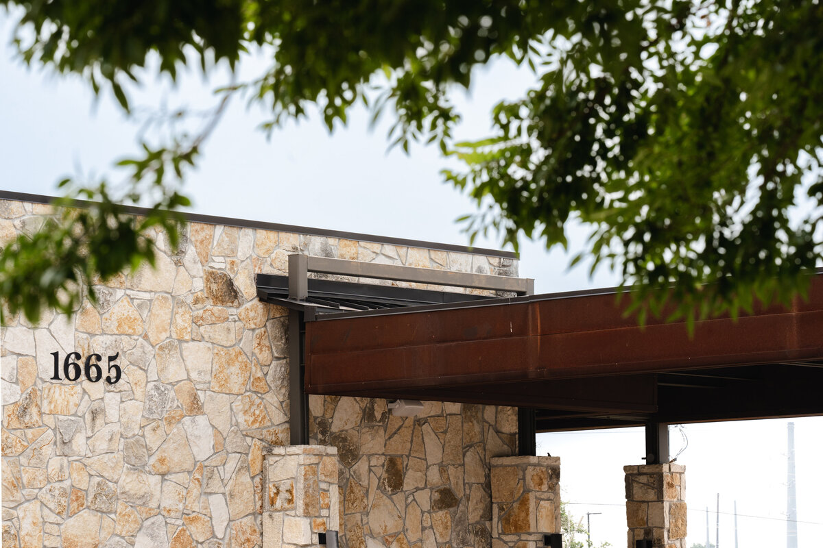 Limestone building facade with corten steel roof overhang for car drive up