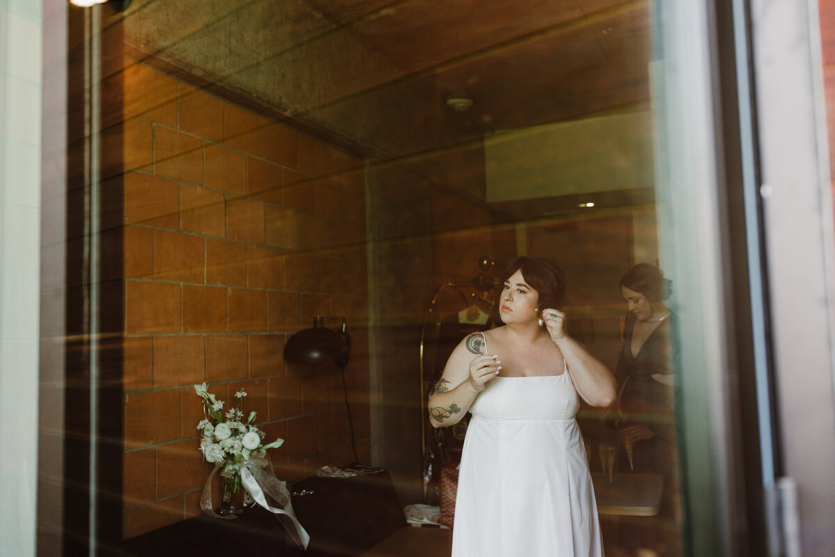 Bride putting earrings in whiist looking out the window at Carpenter Hotel Austin
