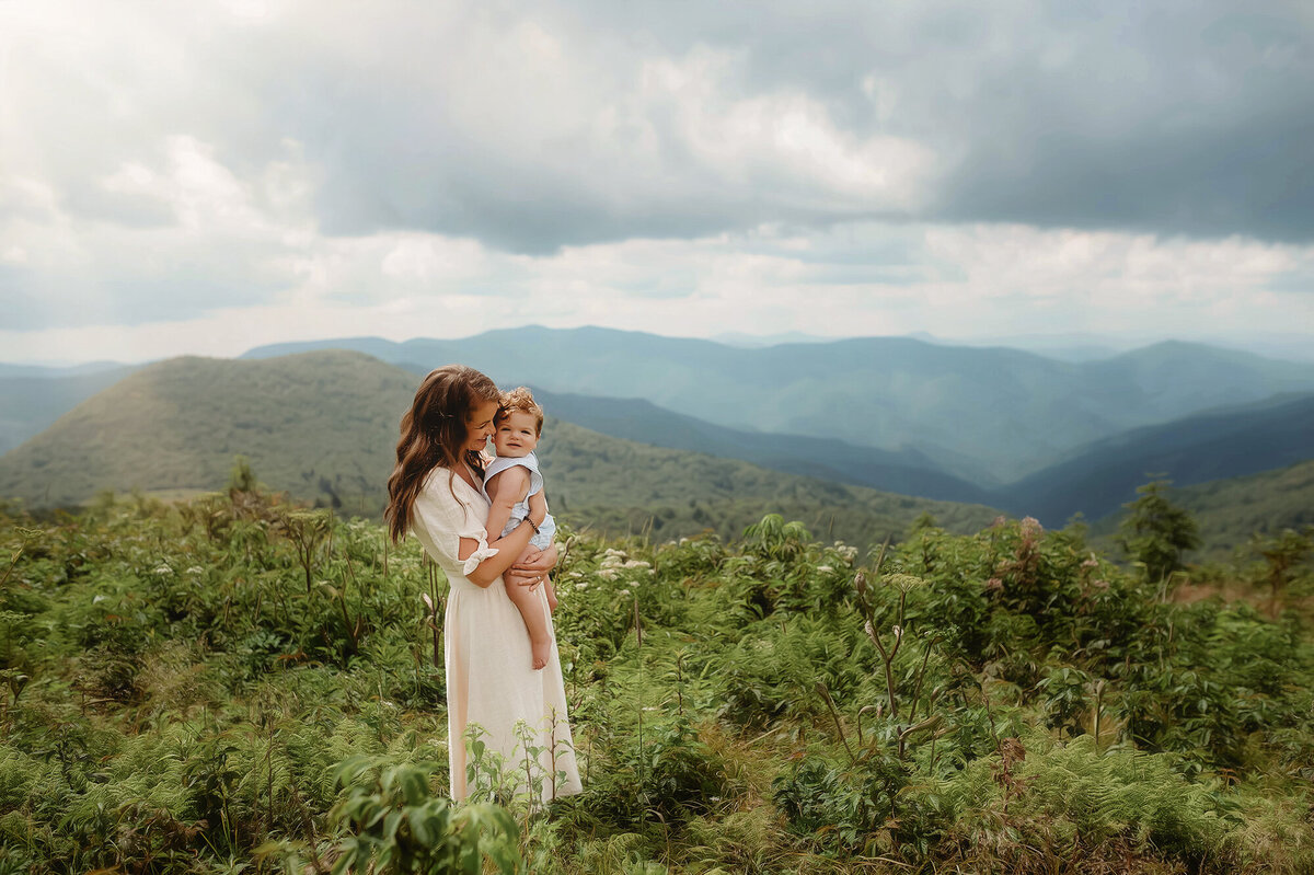 Mother embraces her baby during Family Photos at Black Balsam on the Blue Ridge Parkway  in Asheville, NC.