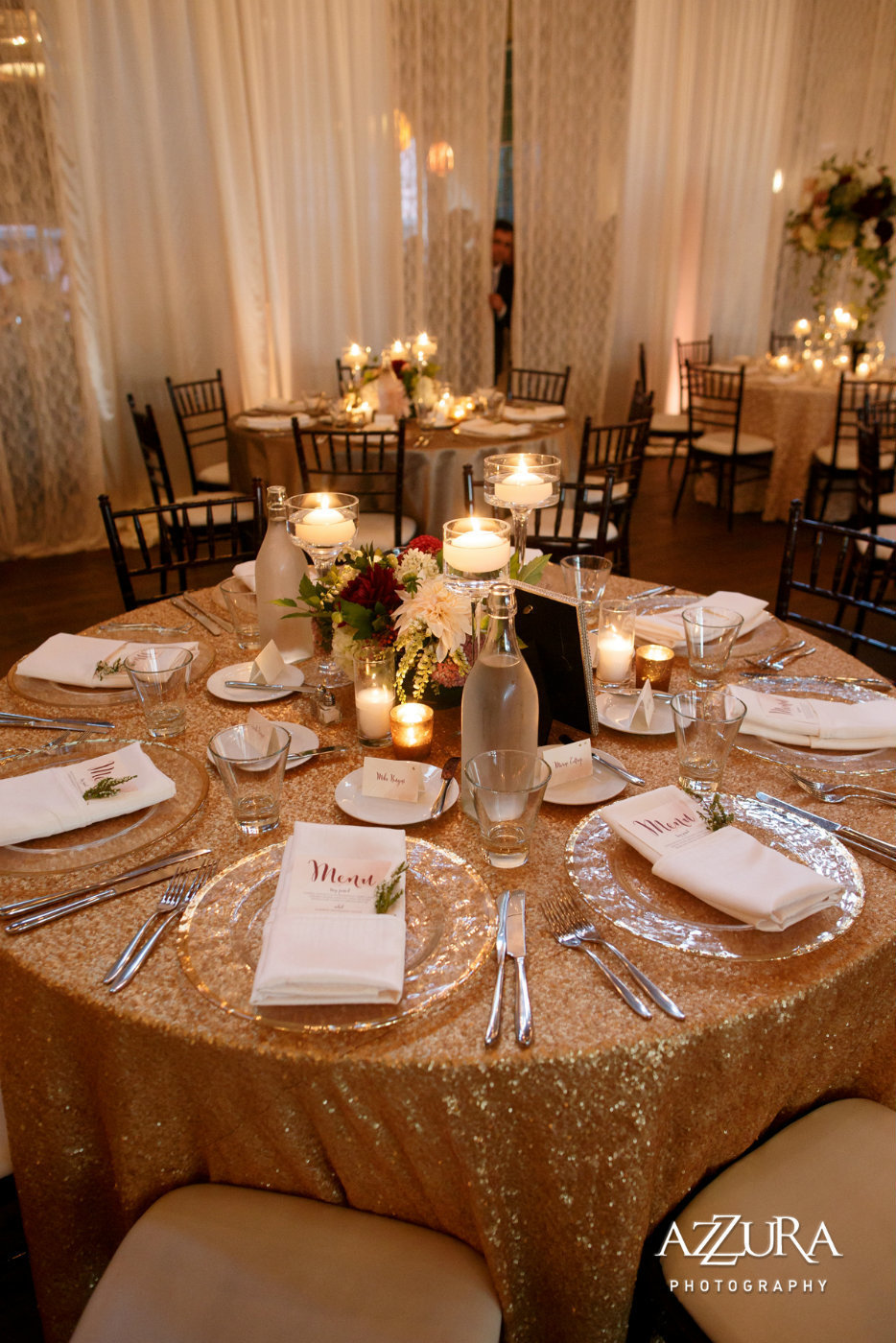 candle centerpiece on blush sequin linen with glass charger plates