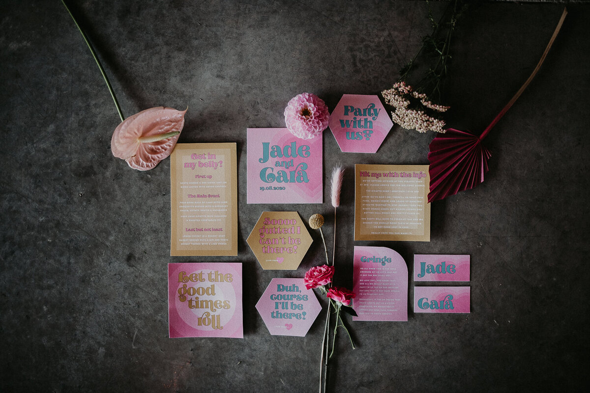 Flat lay photo of pink wedding stationery on a concrete floor