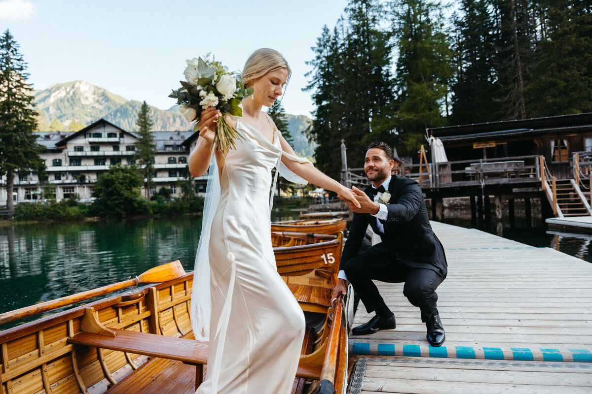 Bride stepping off dock with groom helping after boat ride
