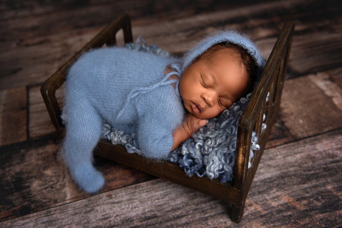 newborn baby in blue posed on bed in Jupiter studio