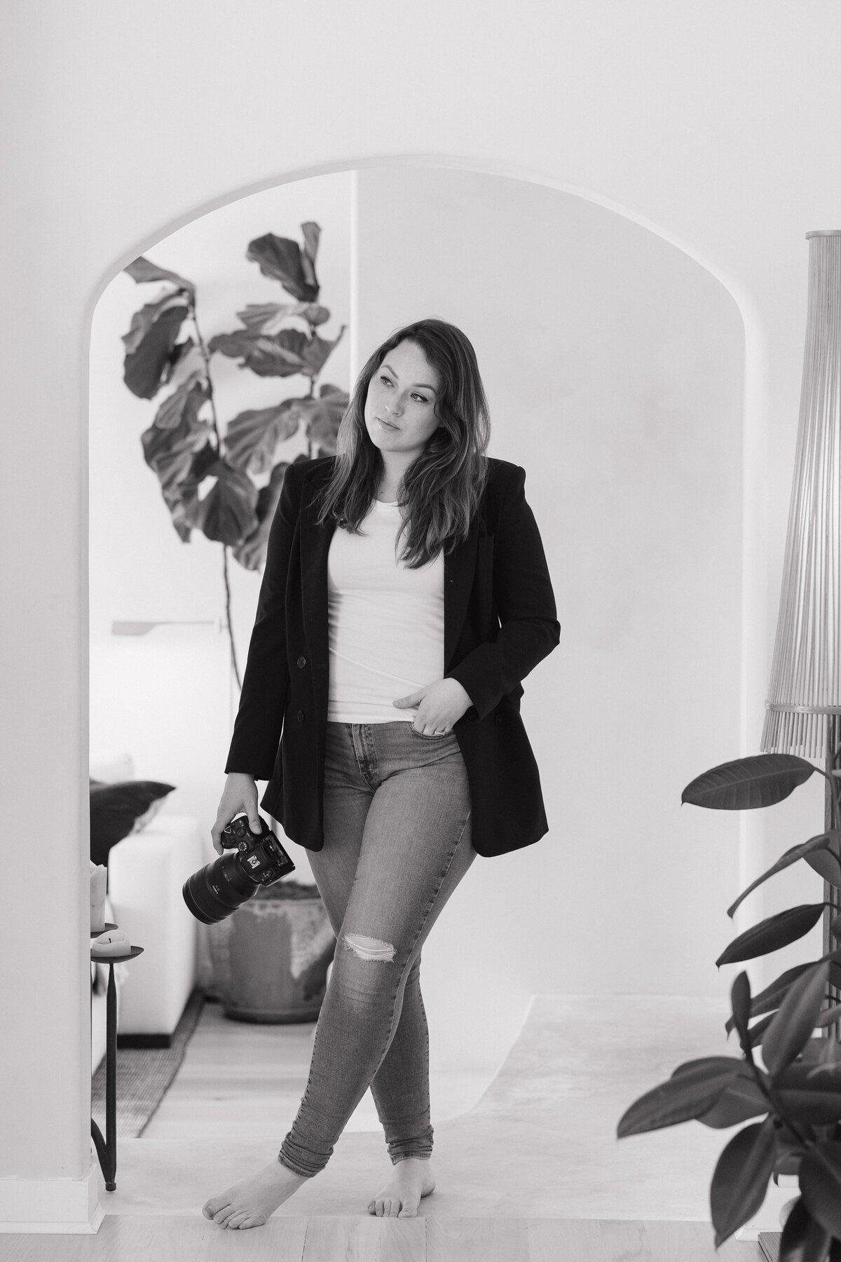 Alyssa Flores, California wedding photographer, holding her camera in a black and white portrait