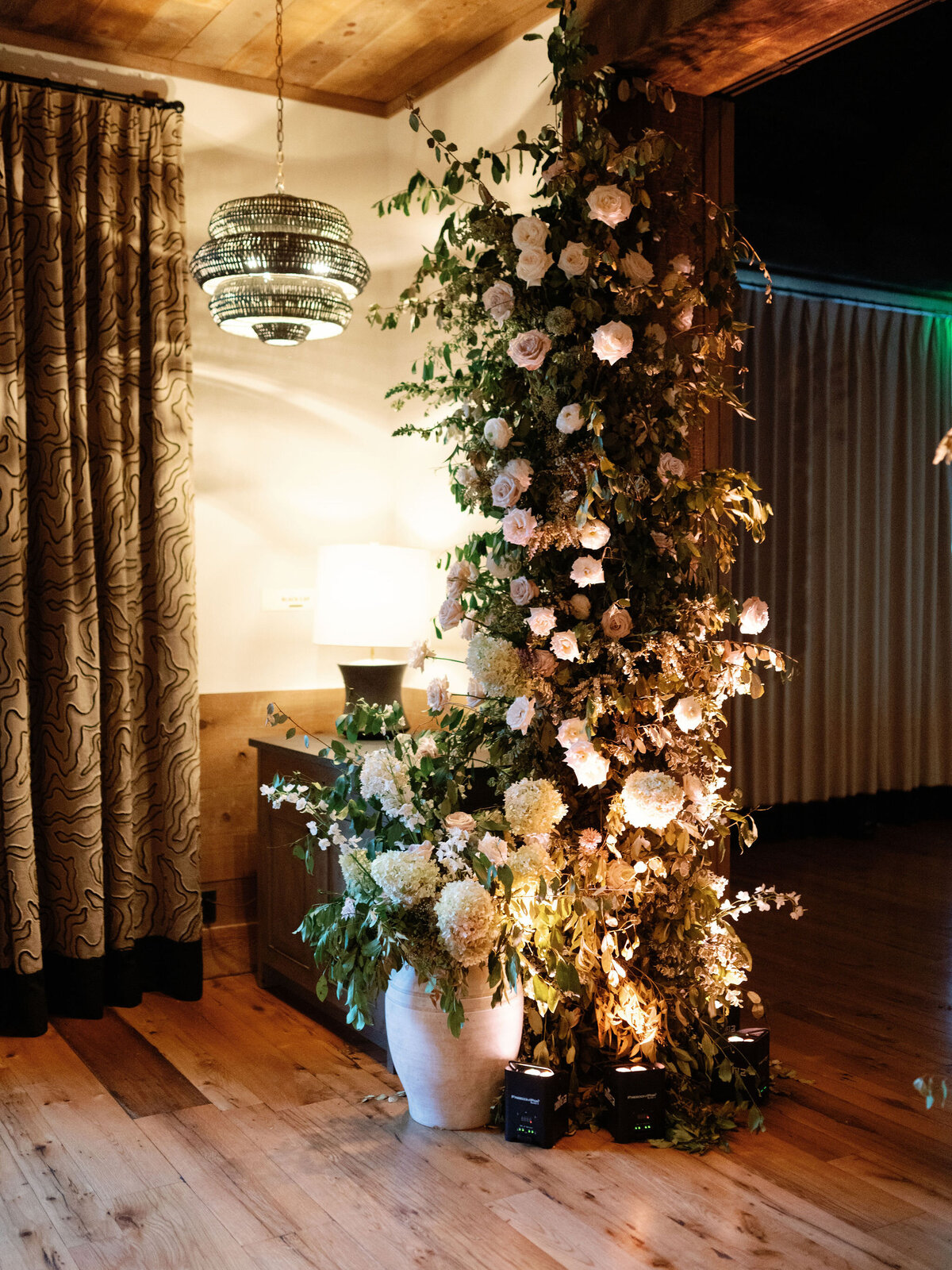 Lush garden inspired floral design growing in Bramble at Blackberry Farm for fall wedding reception. Growing floral installations on chandeliers and ceiling beams create garden setting for fall wedding reception. Timeless and elegant floral design in hues of white, cream, blush, and natural greens. Large trees with floral moments for outdoor wedding reception. Destination wedding at Blackberry Farm. Design by Rosemary & Finch Floral Design in Nashville, TN.
