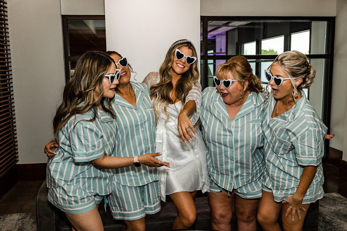 Bride with bridesmaids joking around in heart shaped sunglasses