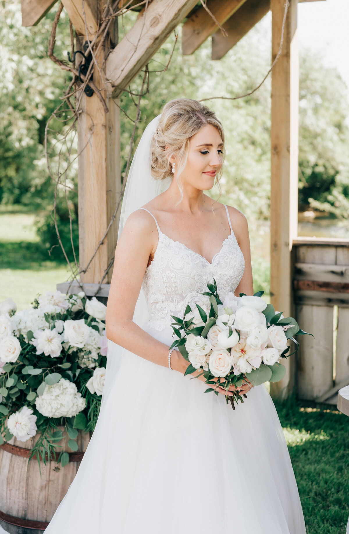 Glamorous bride holding bouquet of white florals and eucalyptus at outdoor wedding ceremony